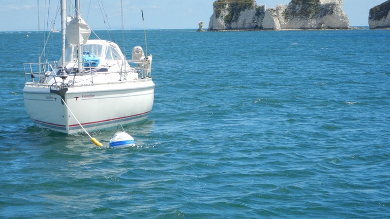 Yacht on eco-mooring with a view of Old Harry Rocks behind.